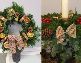 A festive Christmas wreath and centerpiece made from evergreen foliage, holly, dried orange slices, cinnamon sticks, pinecones, berries, and decorative bows, with a white candle featured in the centerpiece.